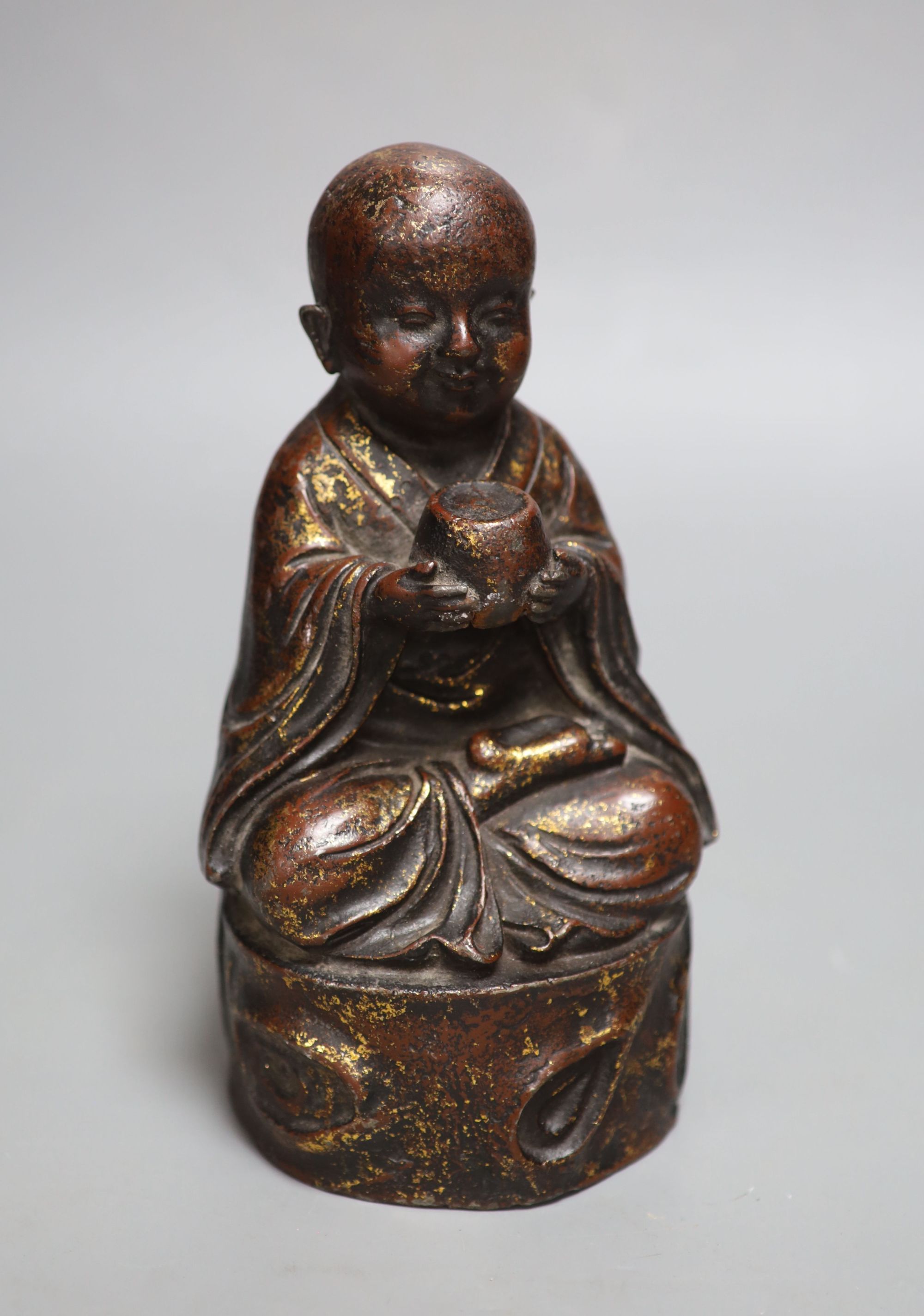 An Oriental patinated bronze seated youth, height 22cm